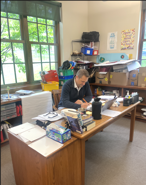 Mr. Halfnight sits working in his middle school classroom. Through teaching Middle School English, he has grown to love teaching students about different texts and how to write. 